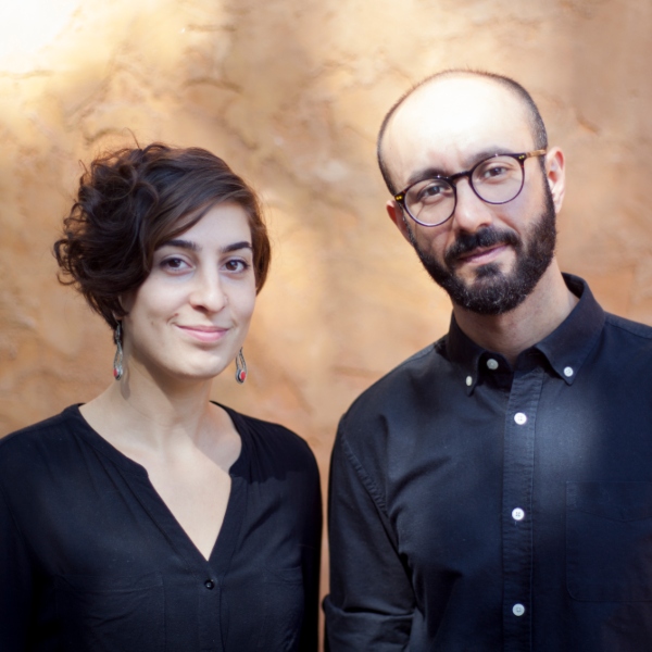 Ariane Lorraine and Shahab Mihandoust wearing black against a tan background