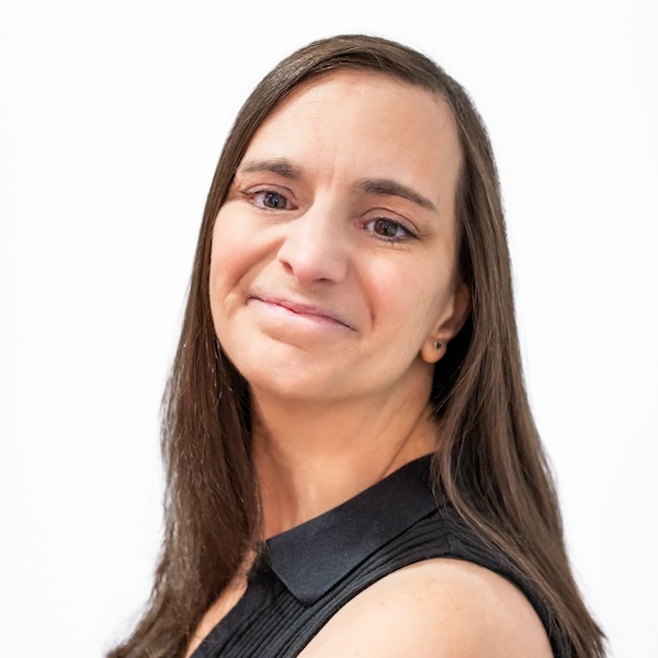 A woman in a black sleeveless dress shirt looks at the camera