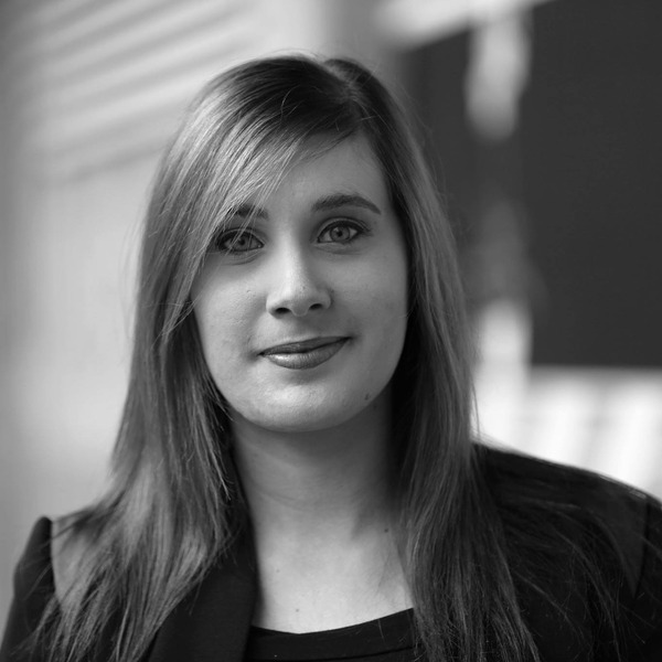 Black-and-white portrait of a woman with straight hair, smiling softly in a blazer.