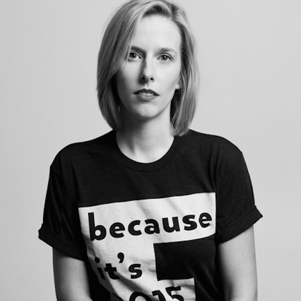 Woman in a "because it’s 2015" t-shirt, seated with a neutral expression in a black-and-white photo