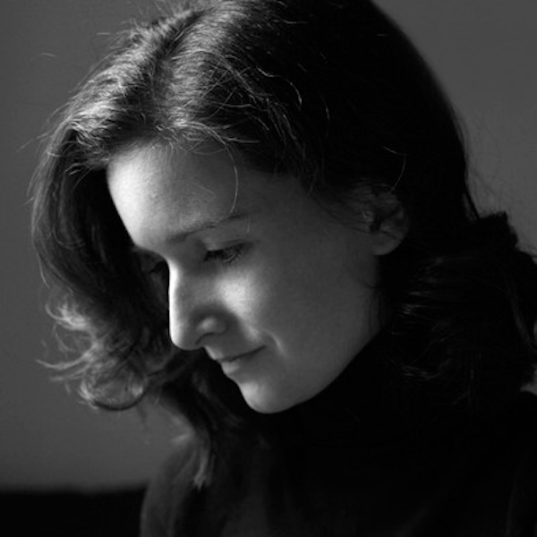 Black and white portrait of a woman in a turtleneck, gazing downward with a gentle smile.