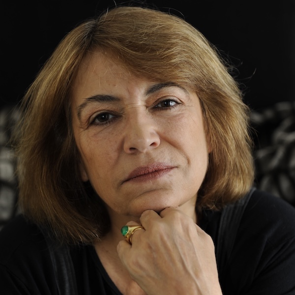 Colour image closeup of a woman with light brown hair. Her head rests on her hand with a gold ring.