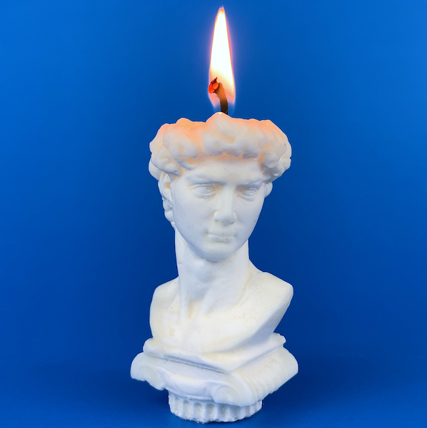 image of greco roman bust candle against blue background