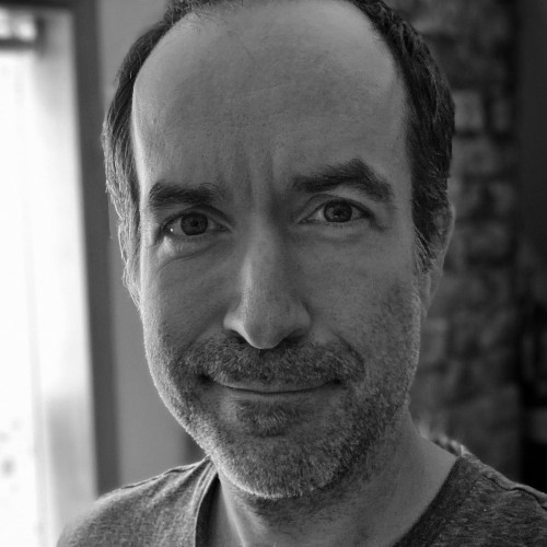 A black and white photo of a white man looking at the camera smiling