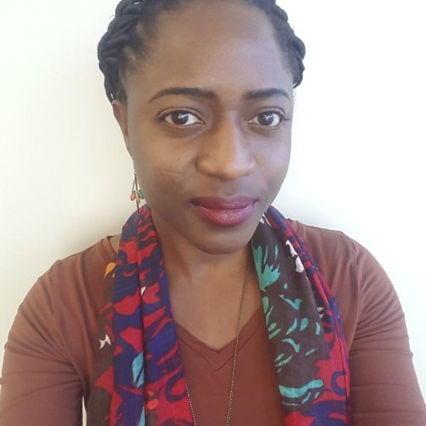 A Black woman with red lipstick, brown eyes wearing a brown shirt with a colourful scarf.