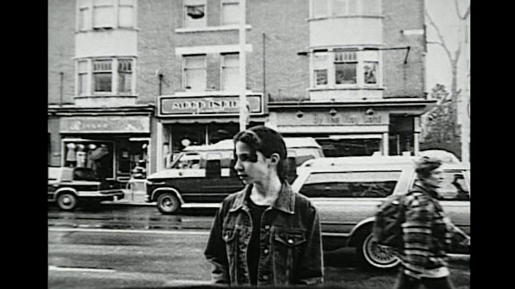 Vue de rue vintage en noir et blanc. Une jeune femme regarde loin de l'appareil photo.
