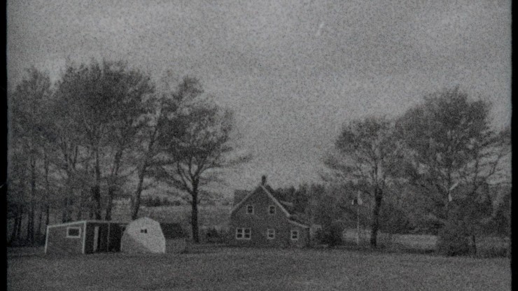 Une photo en noir et blanc d'une maison et d'arbres au loin.