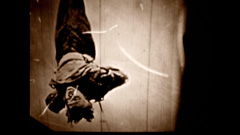A sepia image of Houdini hanging upside down