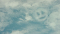 Image of blue sky and clouds, a smily face appears in the top right corner of the clouds.