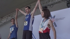 Three athletes on top of a podium holding hands with their arms raised.