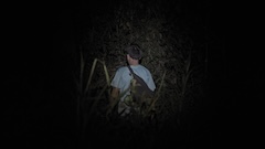 Photo of of the back of a young man taken in a forest at night.