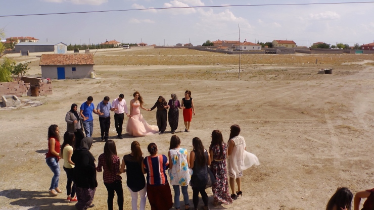 A group of people in a dusty field standing and holding hands in a semi circle