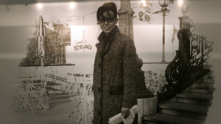 An archival photo of a young boy in an overcoat outside of a cafe