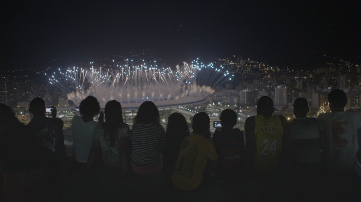 A group of people watch fireworks above the Rio Olympic stadium from a high vantage point
