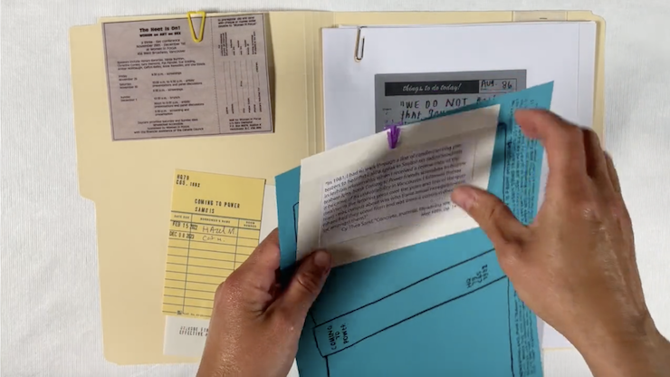 Colour image closeup of a pair of hands holding files from a manila file folder.