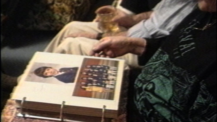 Closeup view of two people sitting side by side and looking at a photo album.
