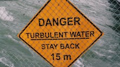 A orange sign that says " Danger turbulent water stay back 15 m