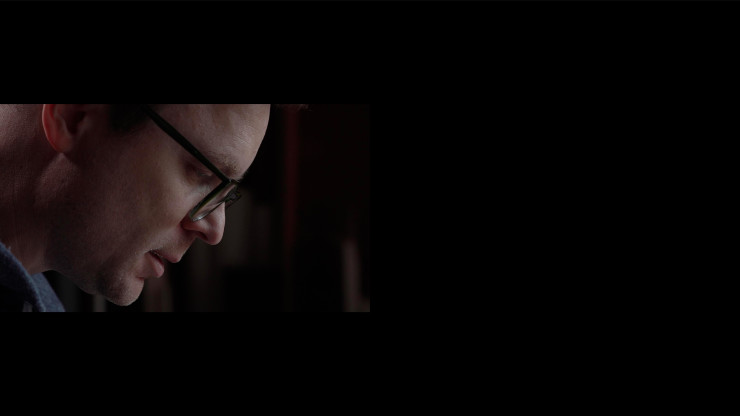 A white man looking down with black glasses 