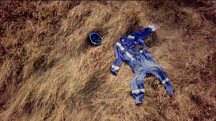 A blue construction outfit laying in a field