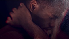 A Black man with his eyes closed in a shower, his hand is holding the back of his neck