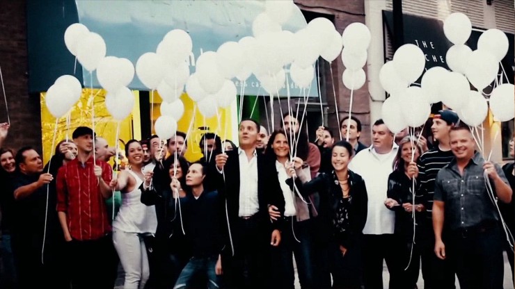 a group of people holding white balloons smiling